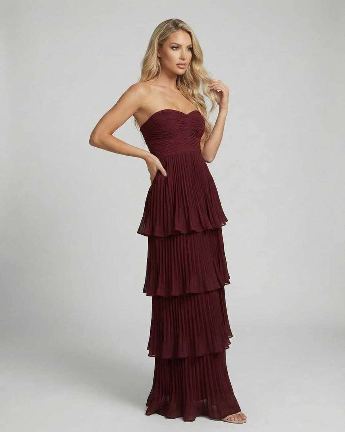 Angled view of burgundy strapless wedding guest maxi dress with tiered chiffon layers