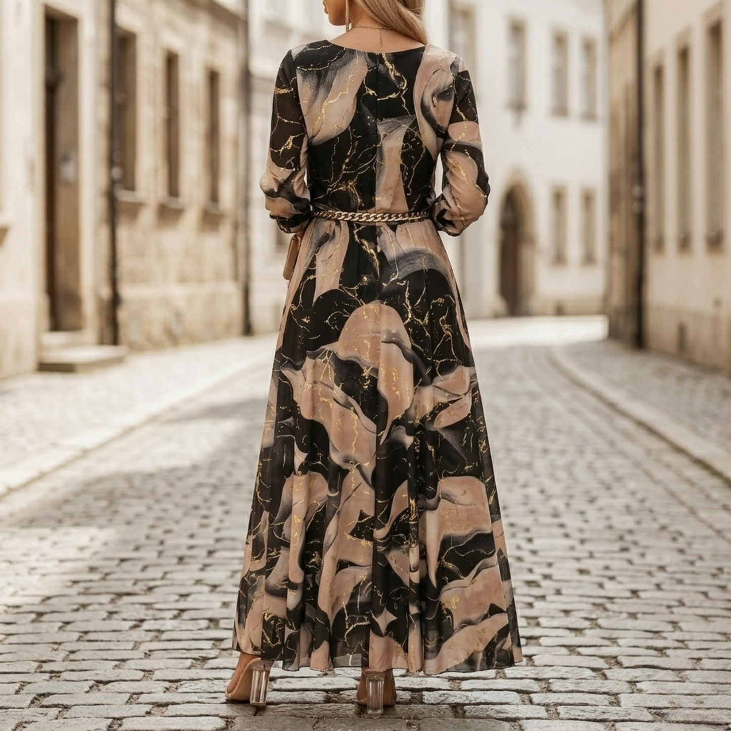 Back view of abstract print maxi dress with long sleeves, flowing skirt, and chain belt detail