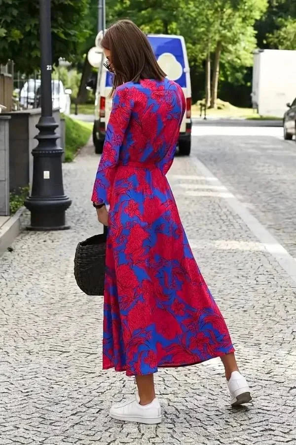 Back view of a women's floral midi dress in magenta and blue with long sleeves and flowing skirt