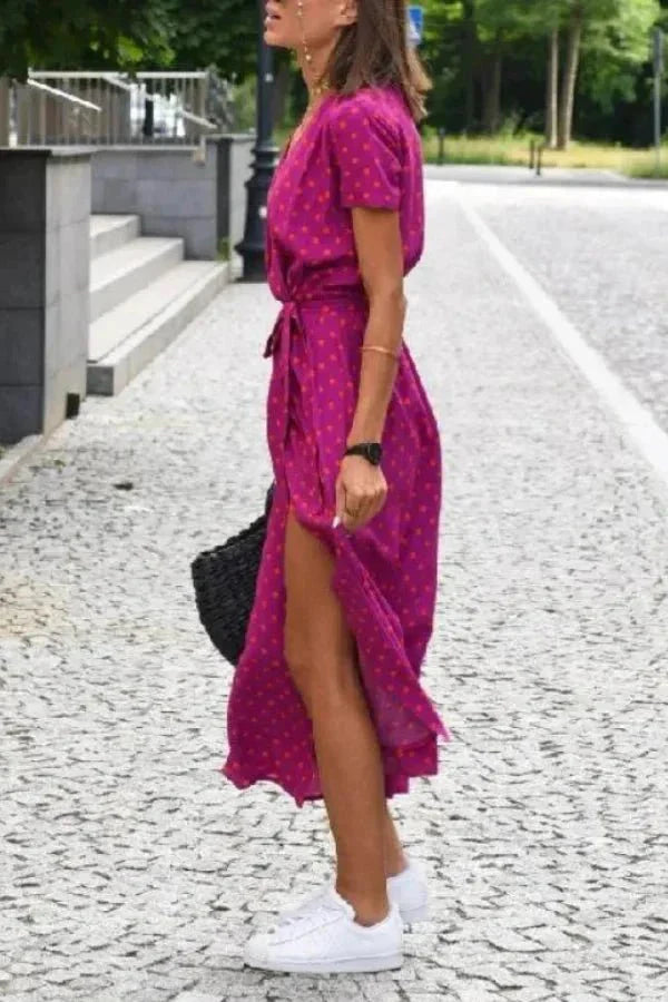 Side view of a magenta polka dot summer dress with V neck, tie waist and midi length hem