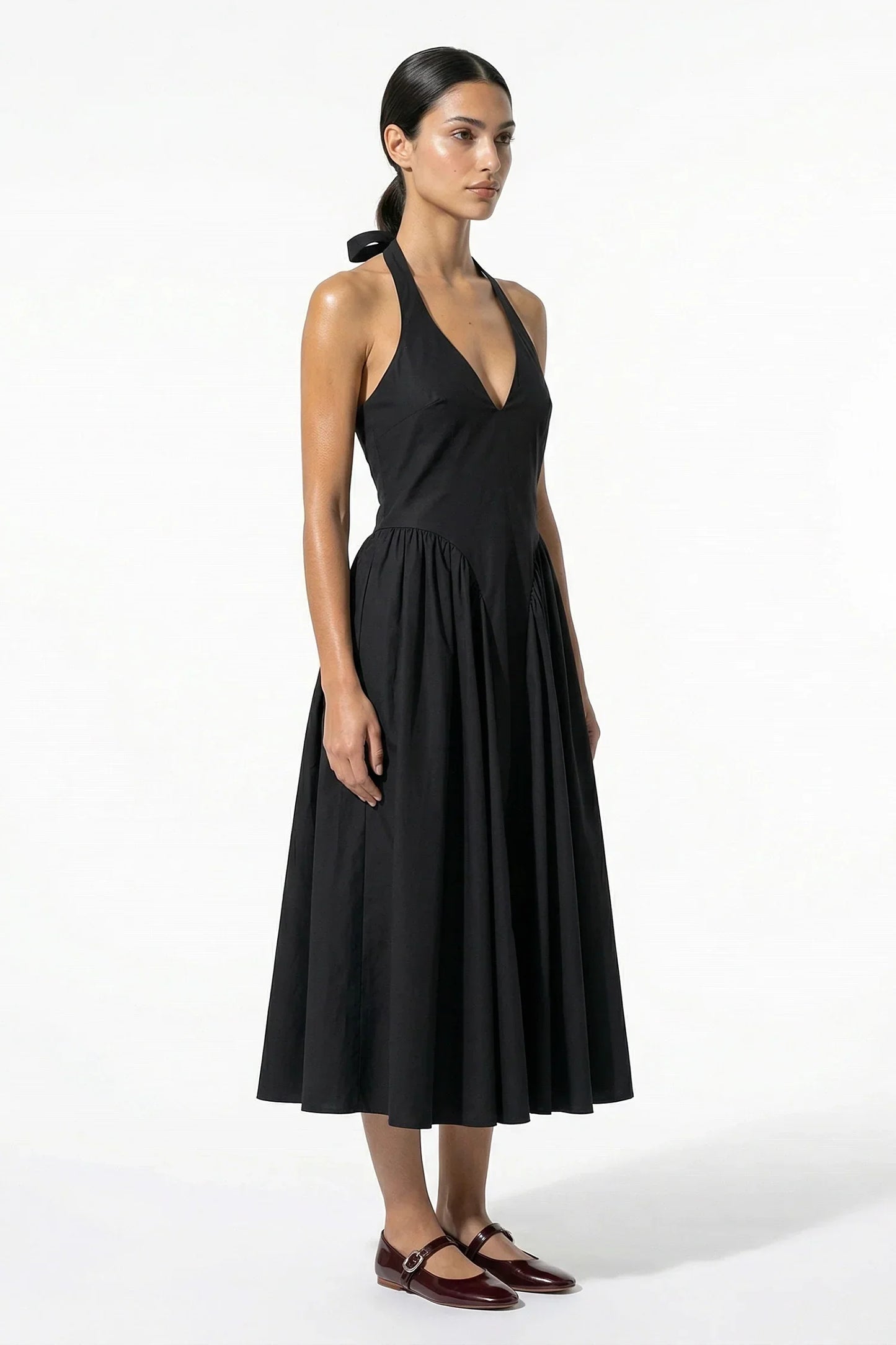 Side view of black halter midi dress showing fitted bodice and flowing skirt