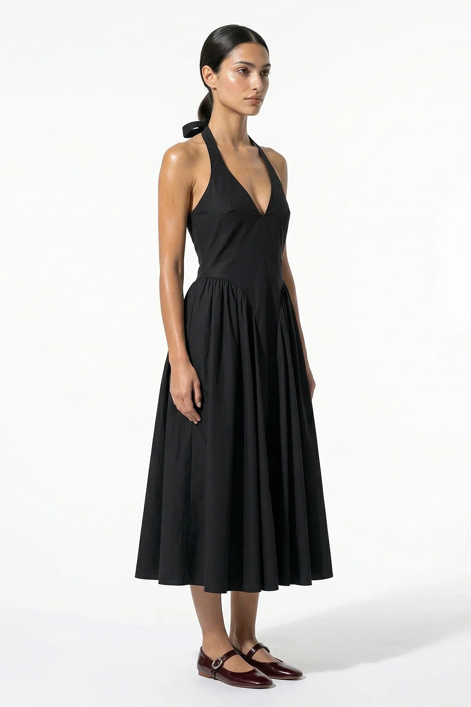 Side view of black halter midi dress showing fitted bodice and flowing skirt