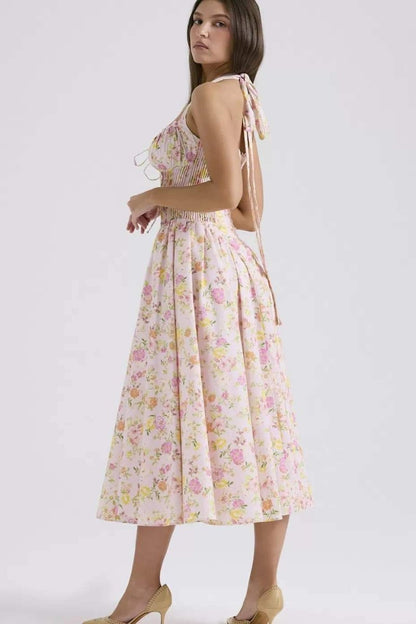 Side view of pink floral halter midi dress showing pleated skirt and fitted bodice