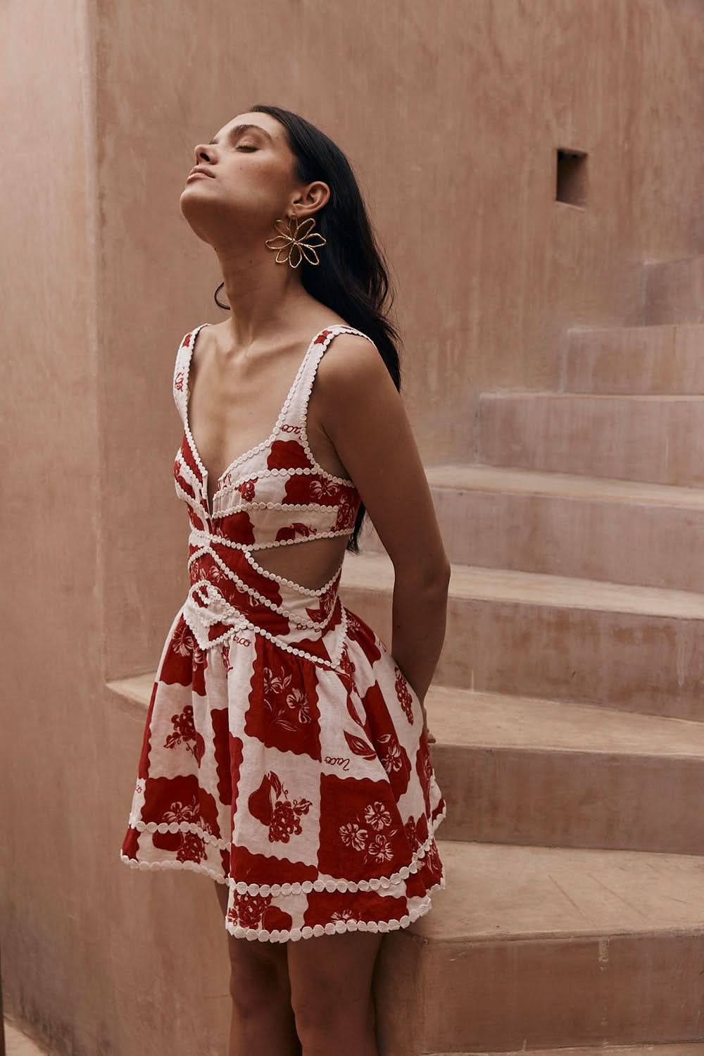 Back view of a red and white floral mini dress with cutout sides and wide straps