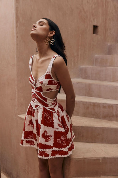Back view of a red and white floral mini dress with cutout sides and wide straps