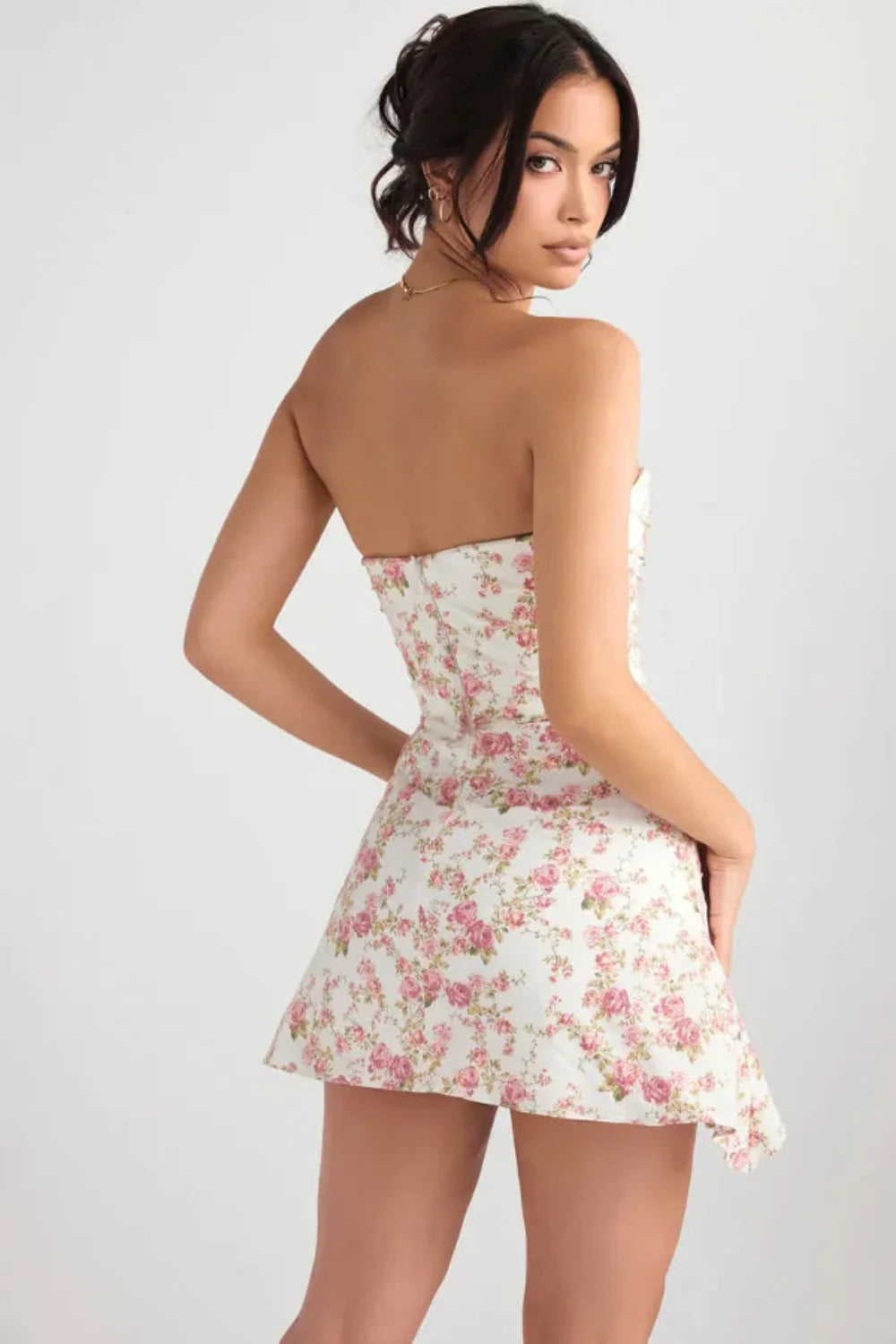 Back view of a floral strapless mini dress with smooth fitted silhouette and side drape detail