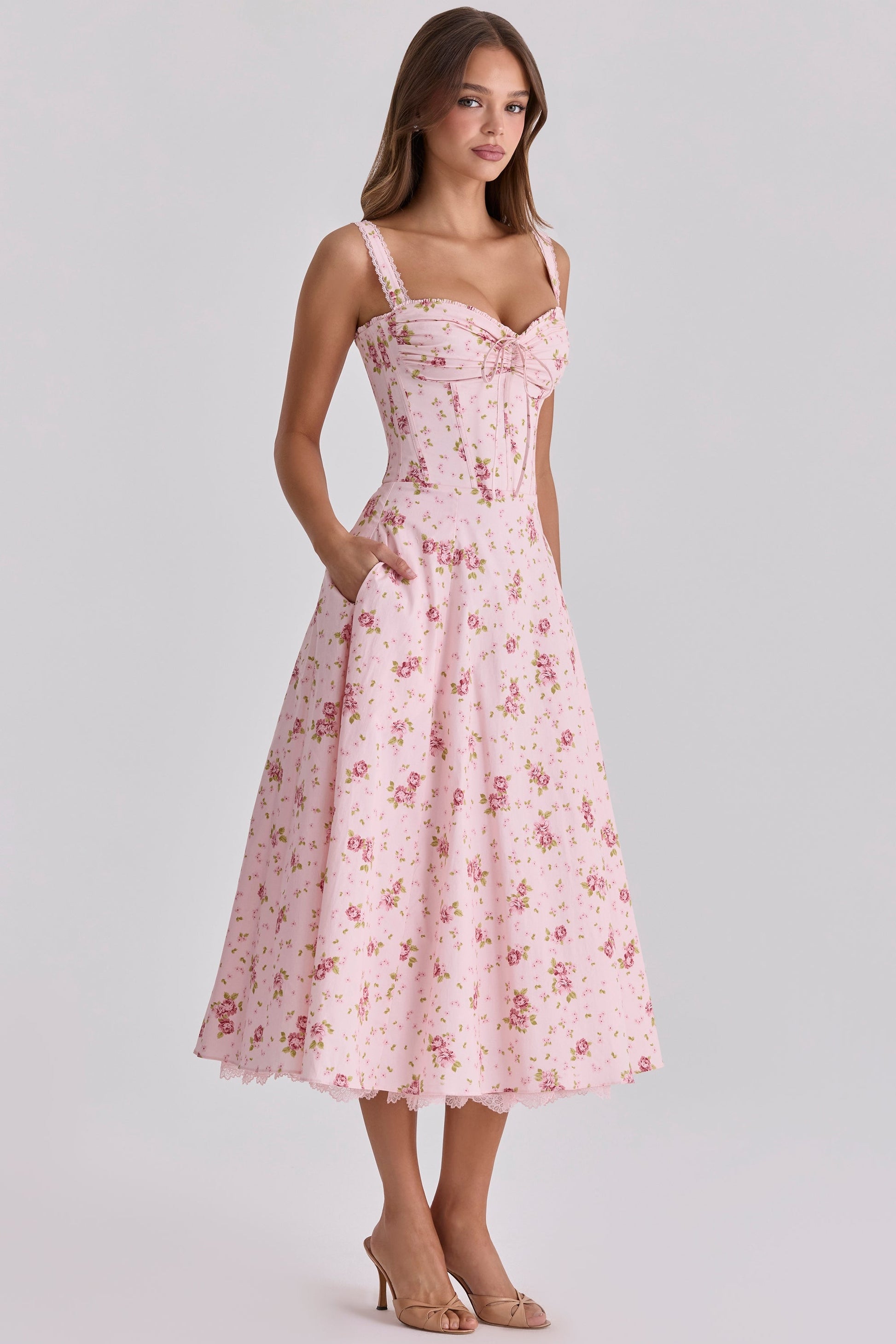 Three-quarter front view of pink floral wedding guest dress with fitted waist and midi length