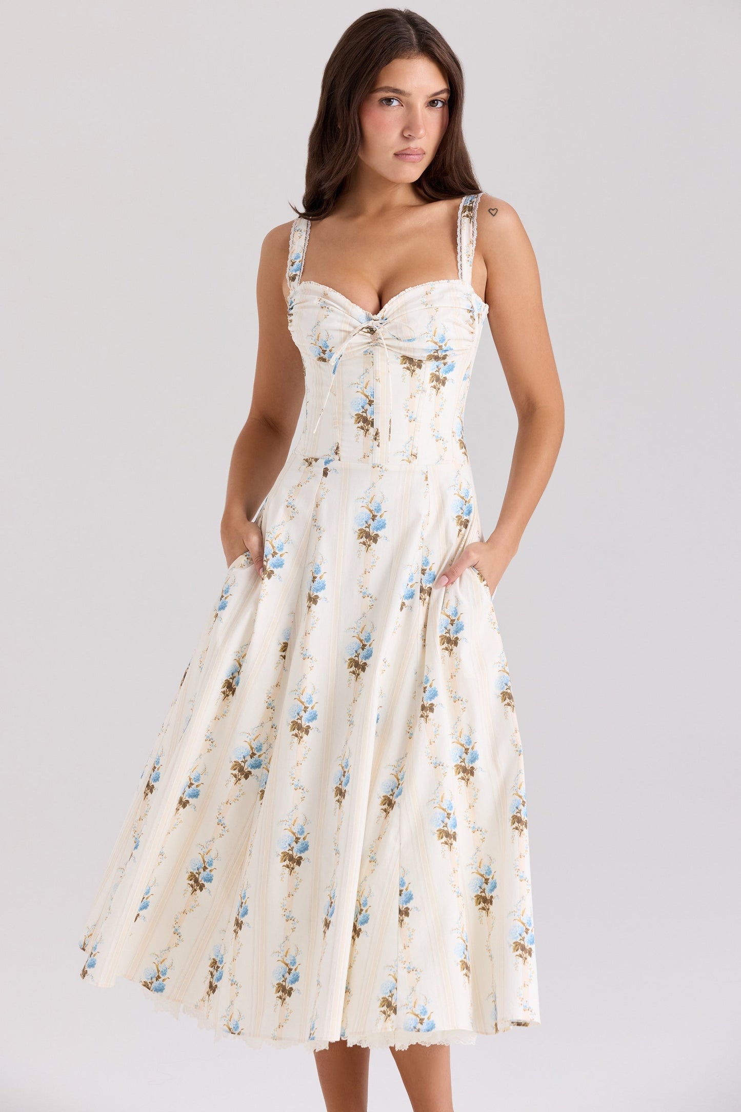 Front view of cream floral sweetheart midi dress with blue flowers and side pockets