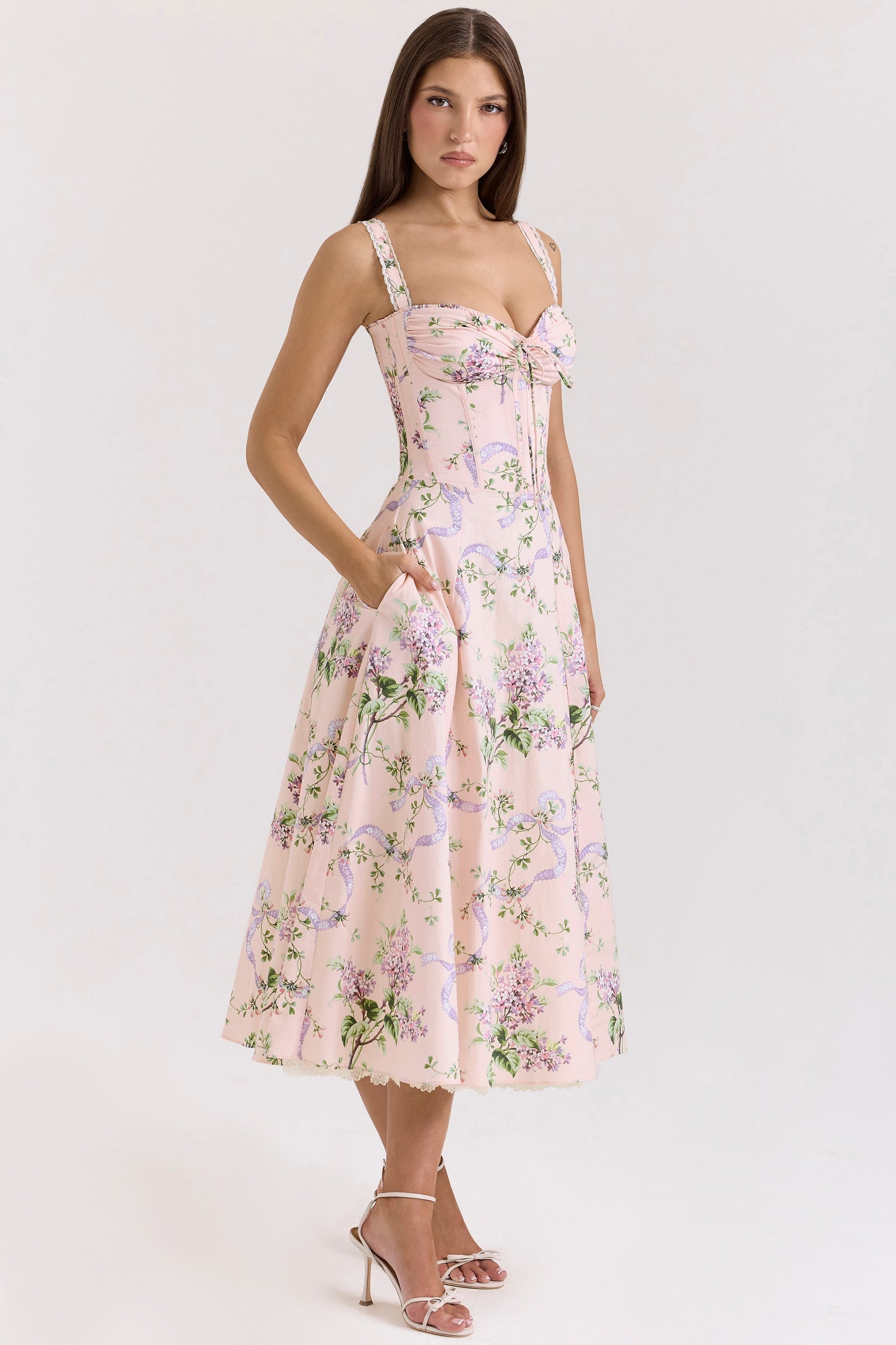 Side front view of pink floral wedding guest midi dress with fitted corset waist