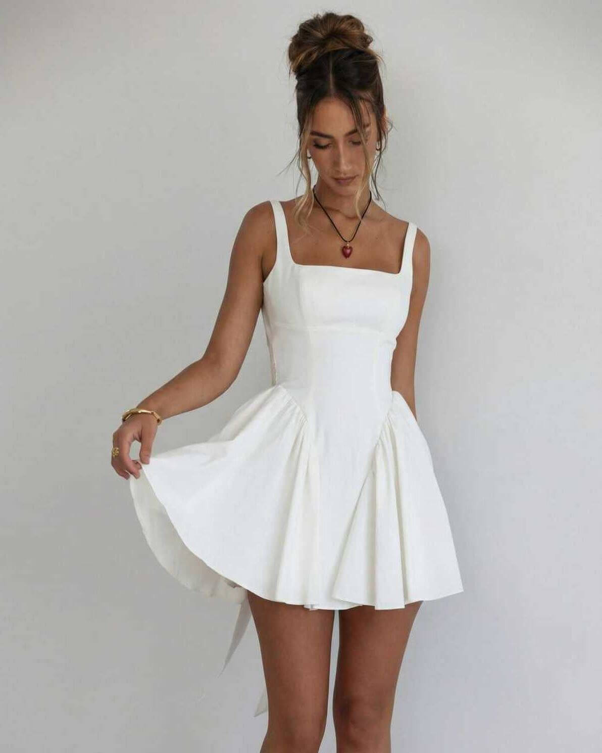 White square neck mini dress with fitted bodice, flared skirt, and open back bow detail