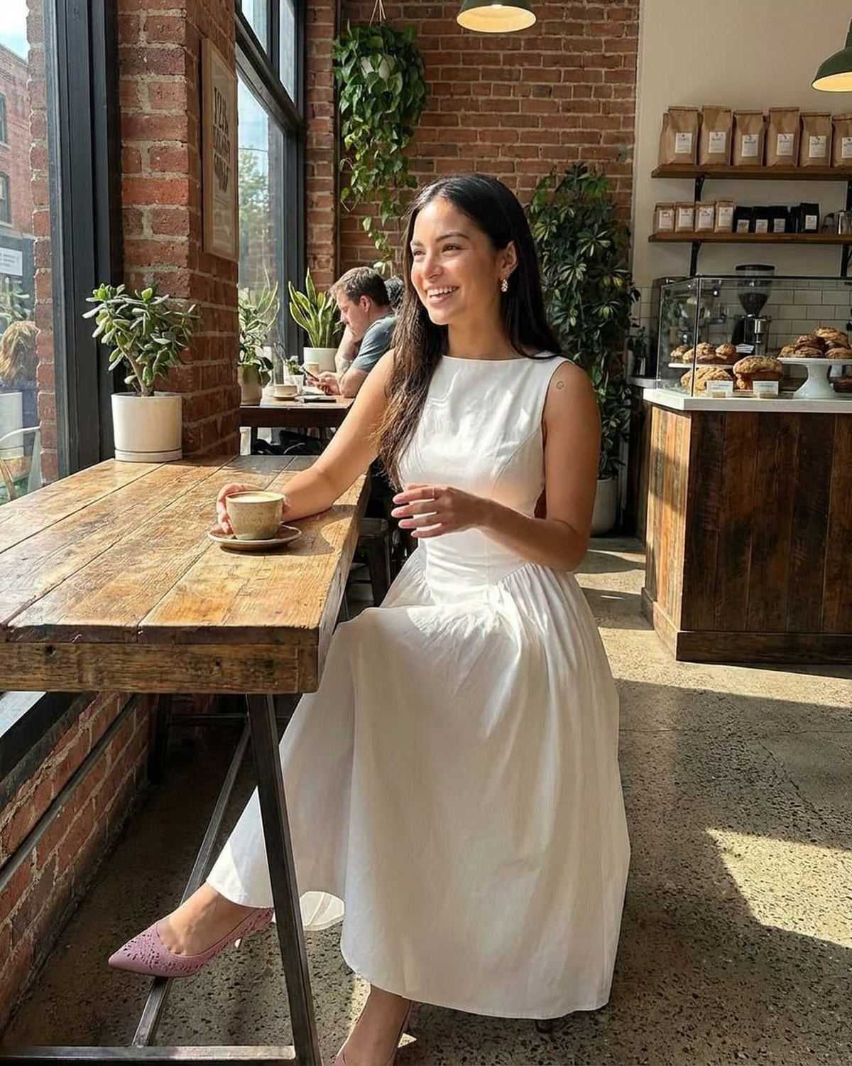 White side cutout midi dress styled in a cafe, showing the sleeveless fit and full skirt