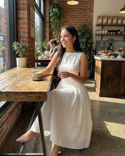 White side cutout midi dress styled in a cafe, showing the sleeveless fit and full skirt